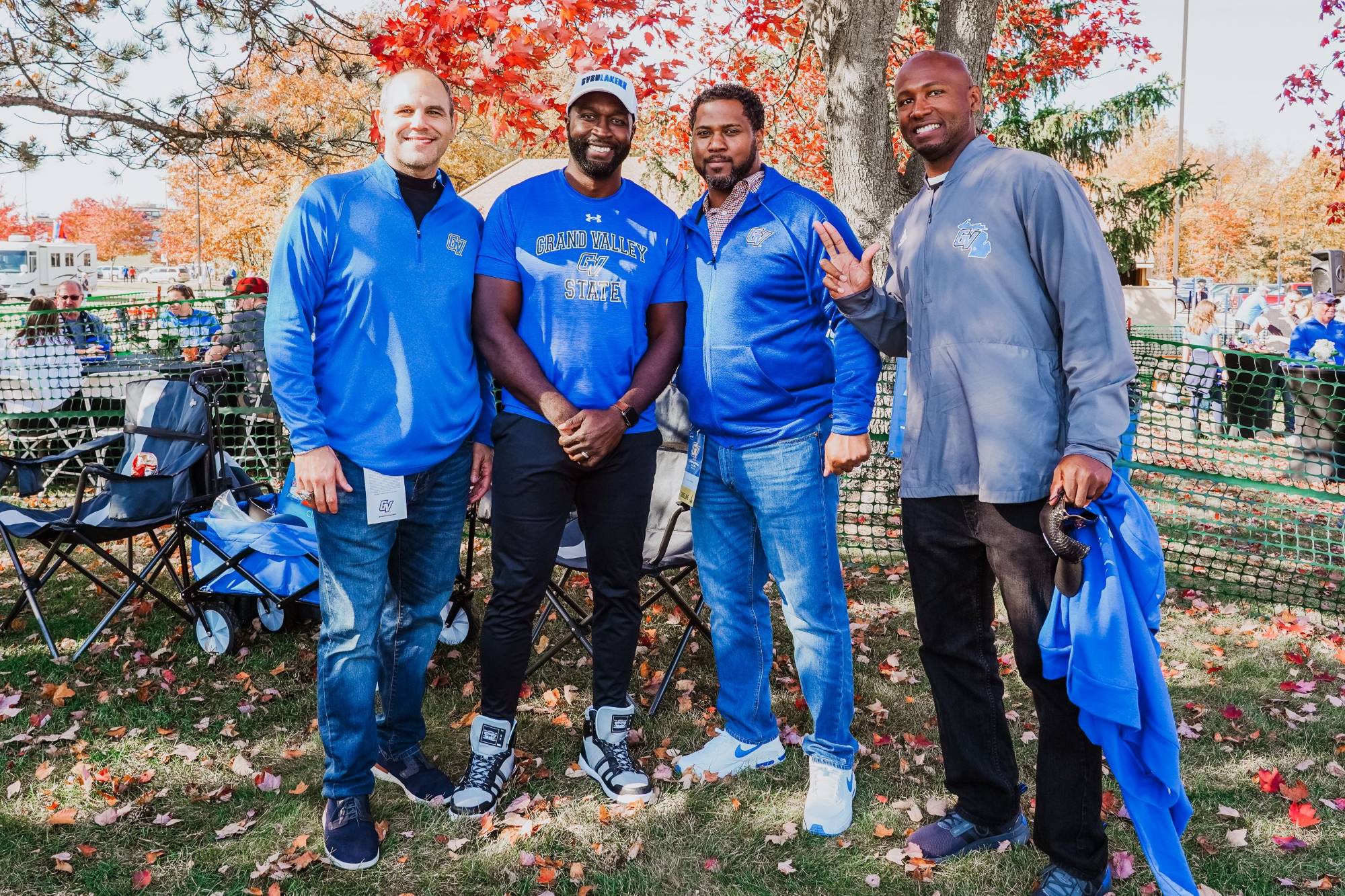 A group of alumni smile and anchor up during the Homecoming tailgate